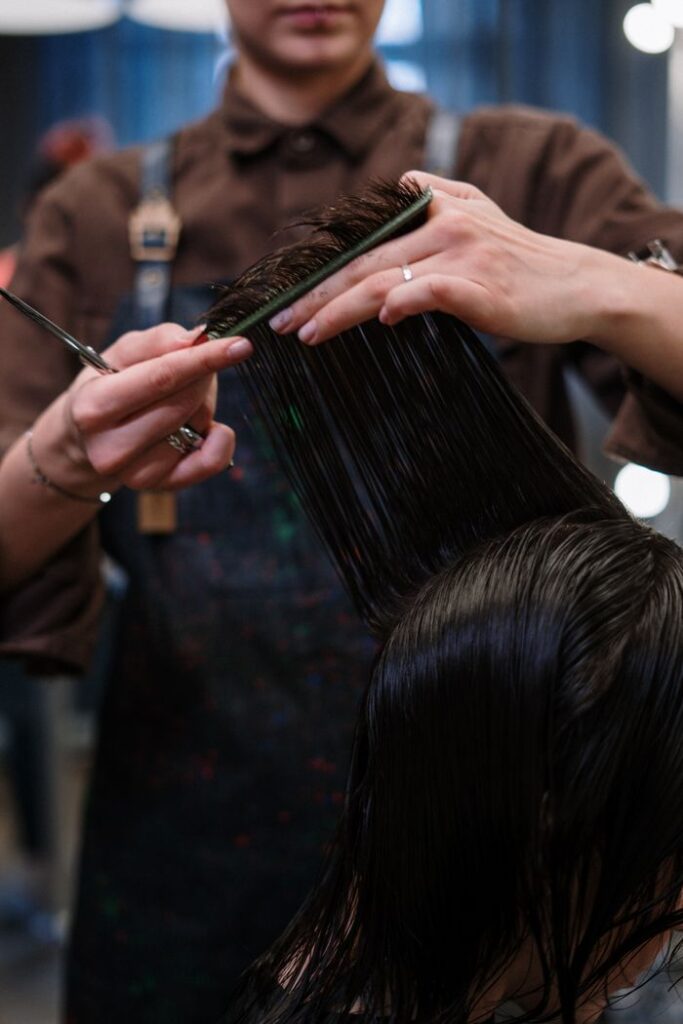 Close-up of a hairstylist cutting wet hair in a professional salon.