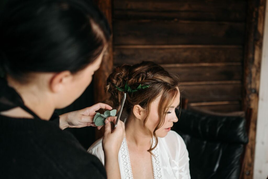 Elegant wedding hairstyle creation with intricate floral accents in a rustic setting.