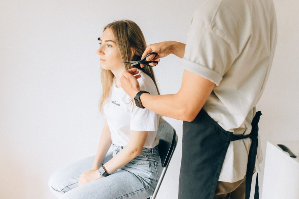 A woman gets her hair professionally cut by a hairstylist in a modern salon.